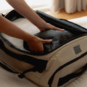 A man putting away packing cubes inside the Kit Bag 40L in Sand