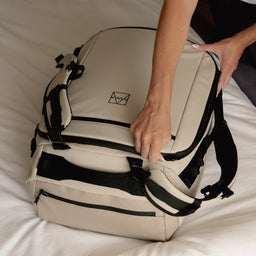 A woman zipping up a Kit Bag 40L in Sand