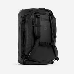 A studio shot of the Kit Bag 40L in All Black standing on its base at an angle showing the shoulder strap