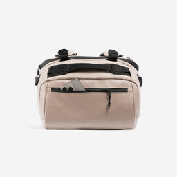 A studio shot of the easy access pcoket with a phone in it on the Kit Bag 40L in Sand
