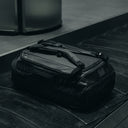 An All Black Kit Bag 65L in the baggage carousel at an airport