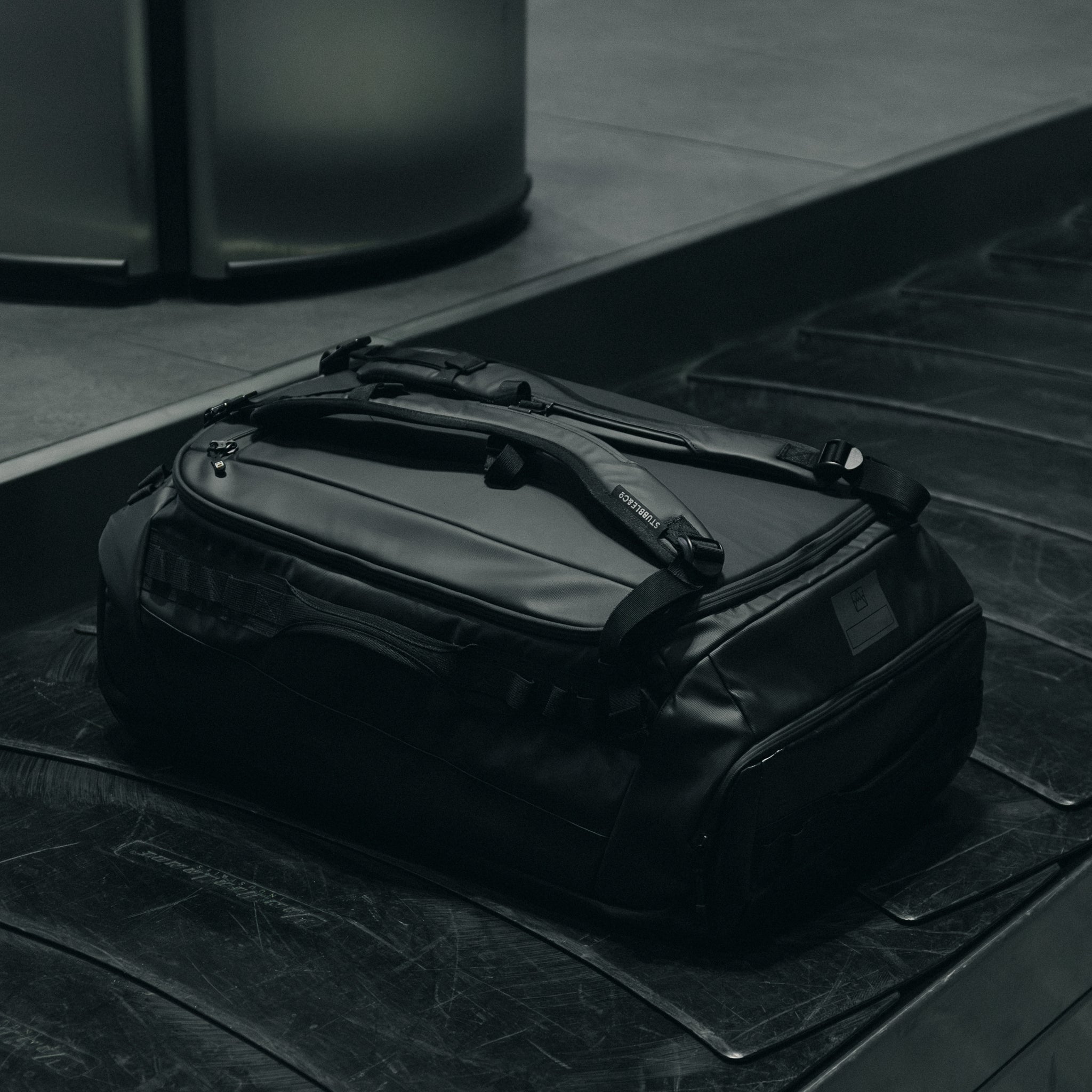 An All Black Kit Bag 65L in the baggage carousel at an airport