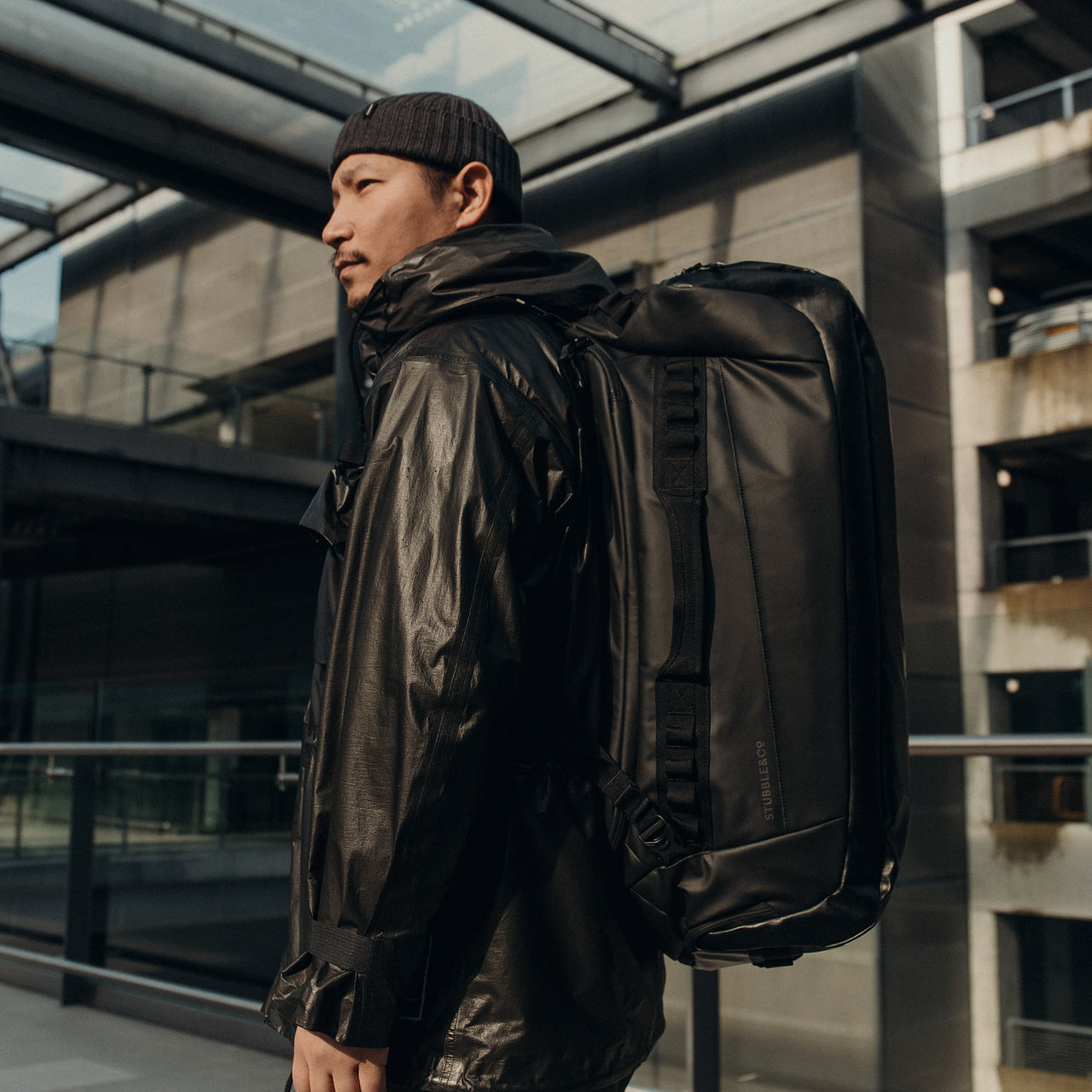 A man wearing an All Black Kit Bag 65L on his back