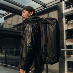 A man wearing an All Black Kit Bag 65L on his back
