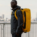 A man wearing a Kit Bag 65L in Yellow on his back