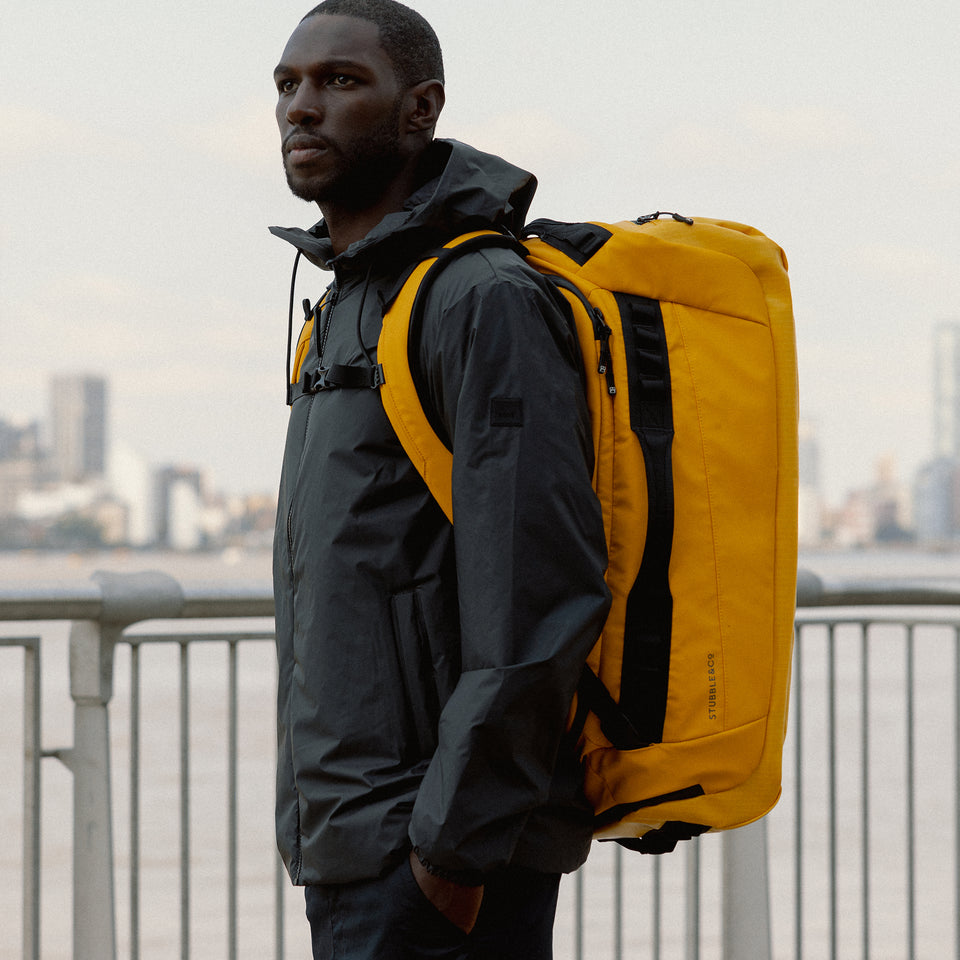 A man wearing a Kit Bag 65L in Yellow on his back