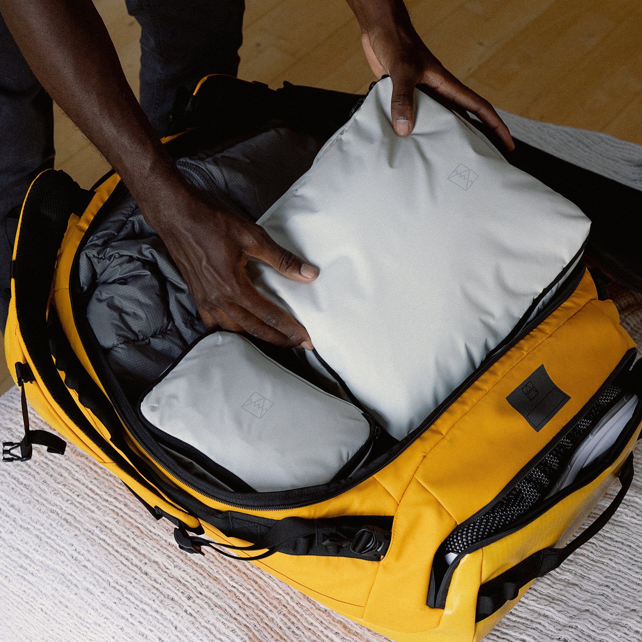 A man packing a Kit Bag 65L in Yellow using Stubble & Co's packing cubes