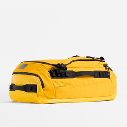Kit Bag 65L in Yellow resting horizontally on a plain white background. 