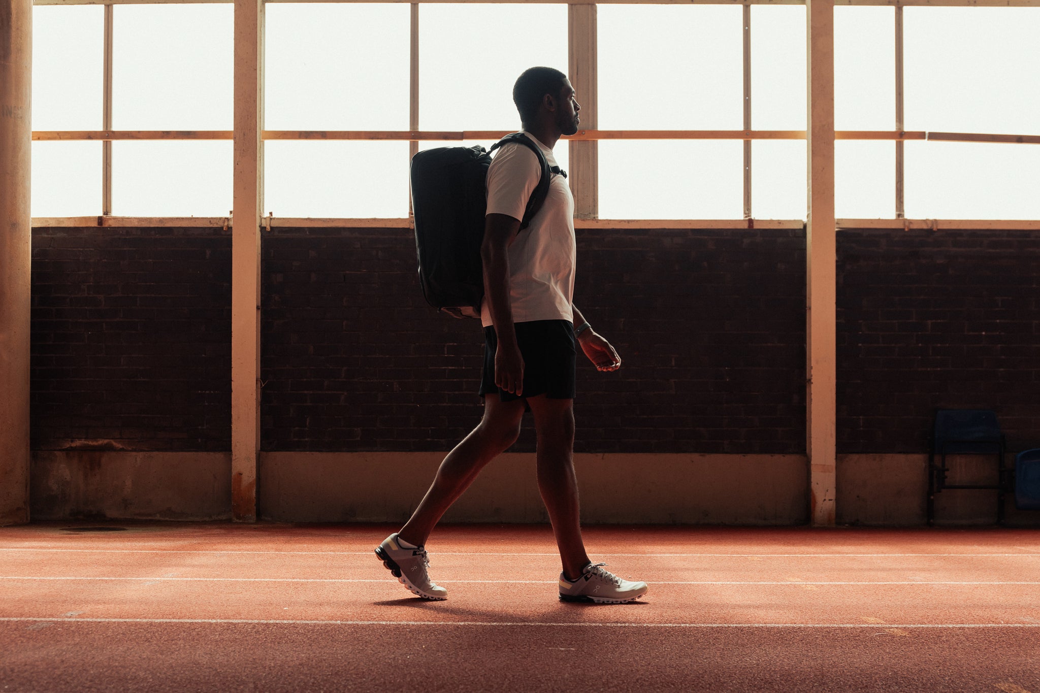 Man with backpack on walking in a gym