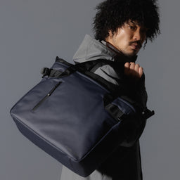 A man wearing a Midnight Blue Laptop Tote 20L over his shoulder