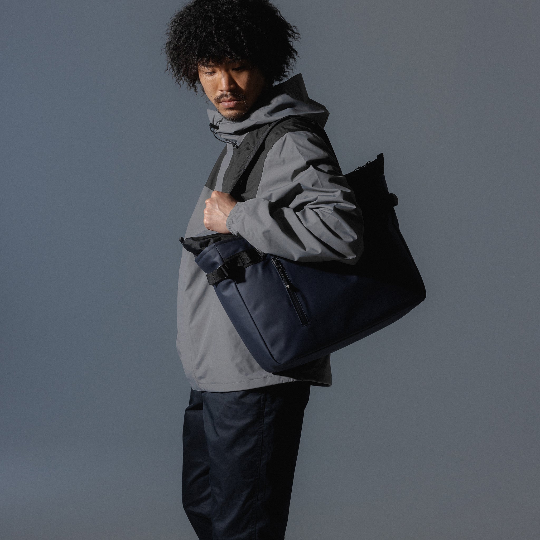 A man carrying a Midnight Blue Laptop Tote 20L bag on his shoulder