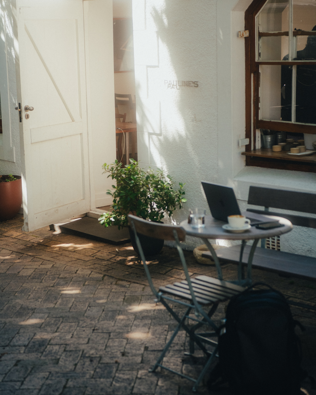 A table, chairs, and laptop set up outside Pauline's Cafe on a sunny day in Cape Town