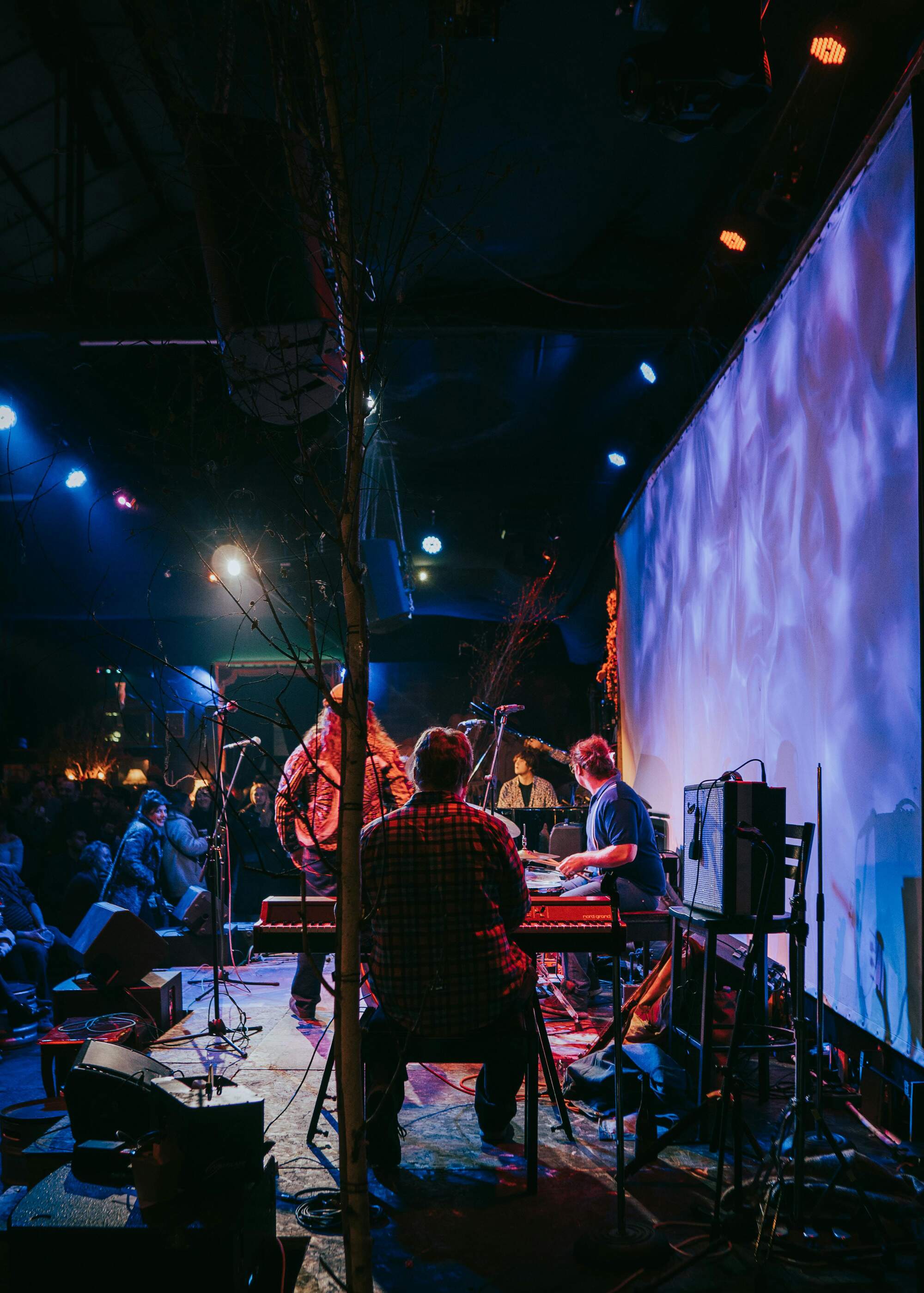 Band performing on stage with a large colourful screen in the background