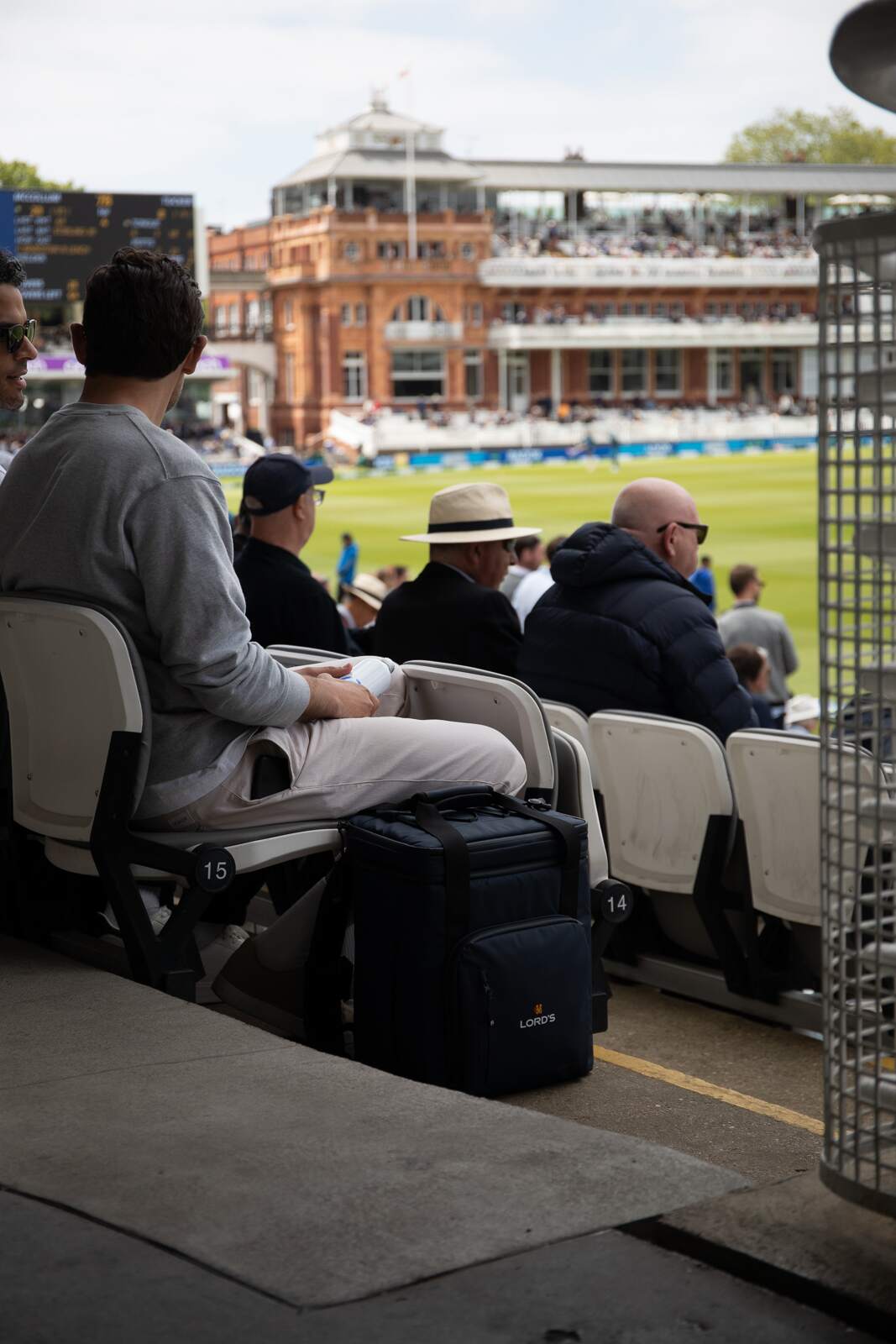 People sitting in chairs with a Cooler at a cricket match