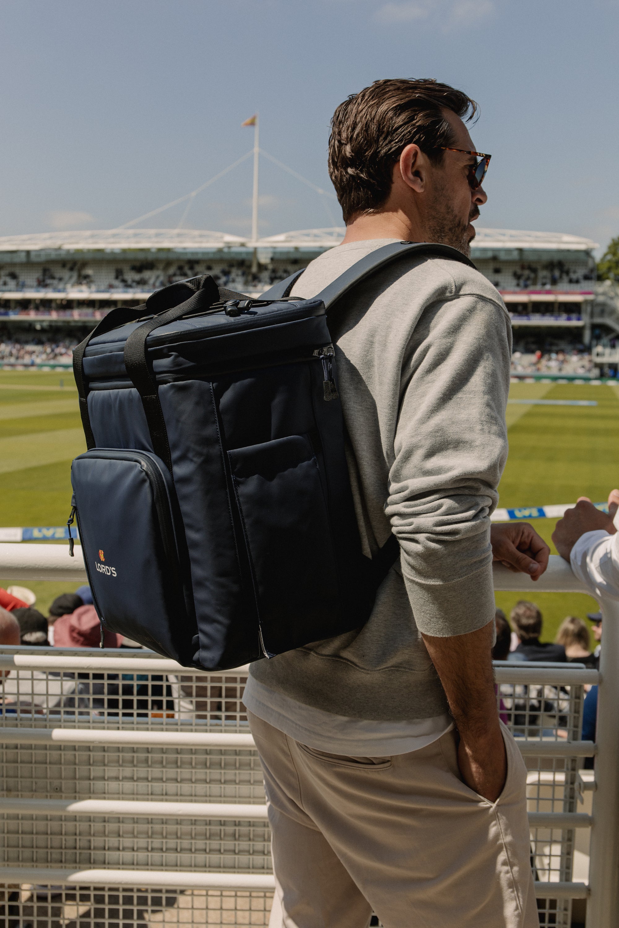 Man wearing navy cooler backpack at the cricket