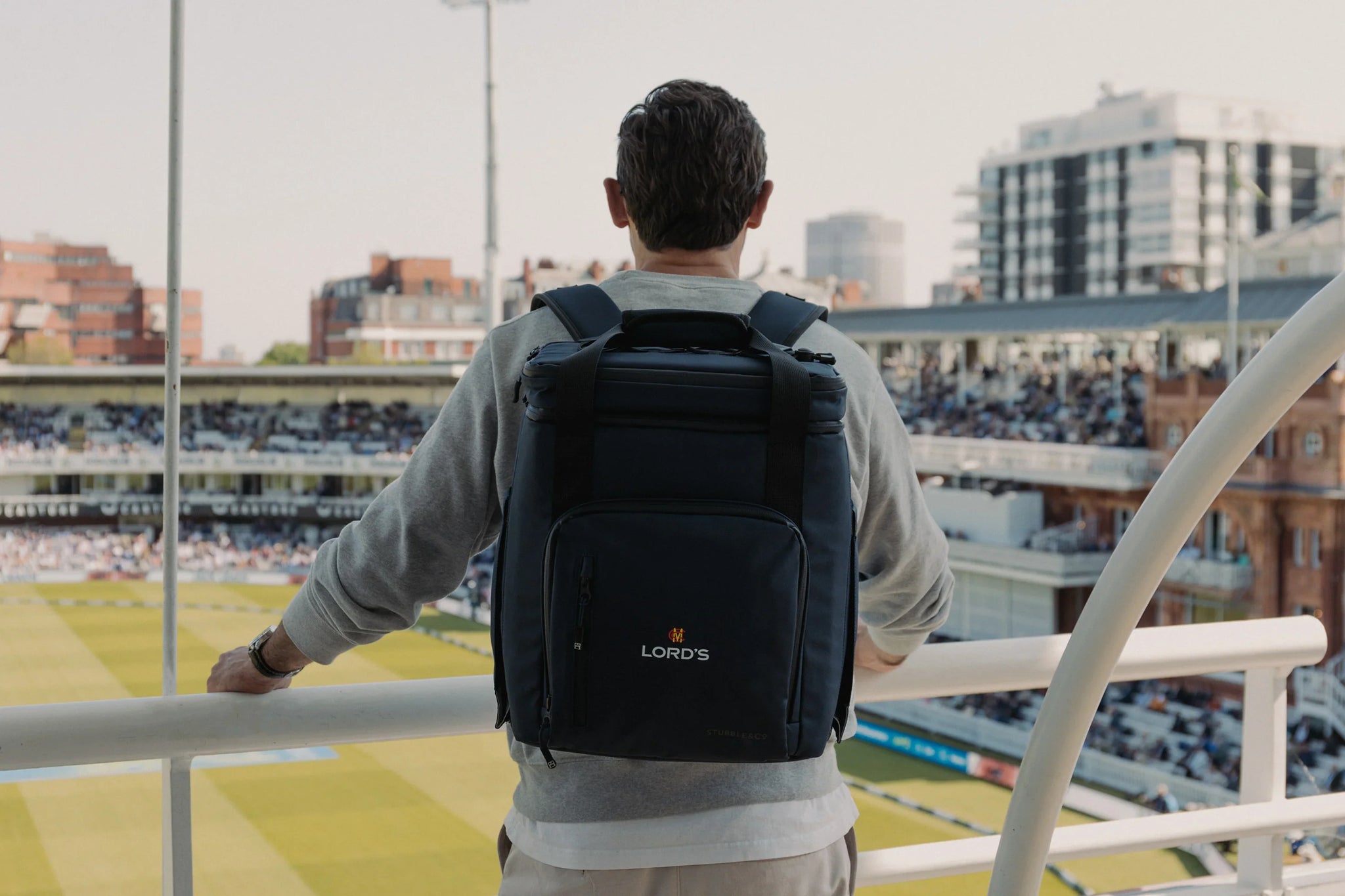 Man wearing navy cooler backpack at the cricket