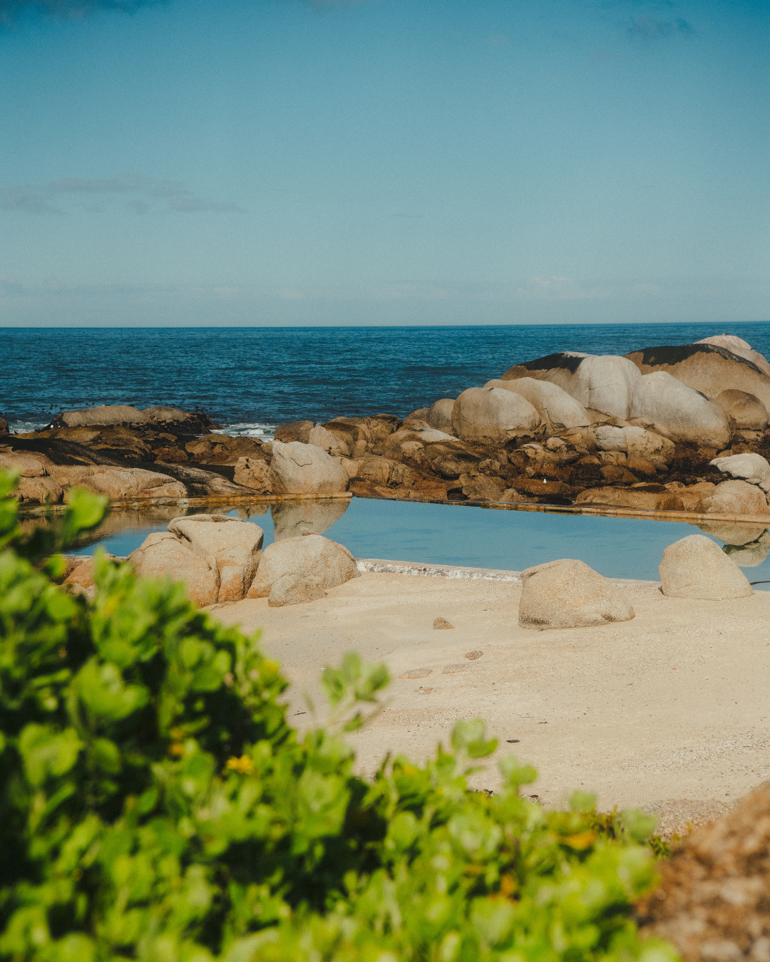 Maiden's Head Cove in Cape Town, rock formations surround the pool and green foliage grows to the left side