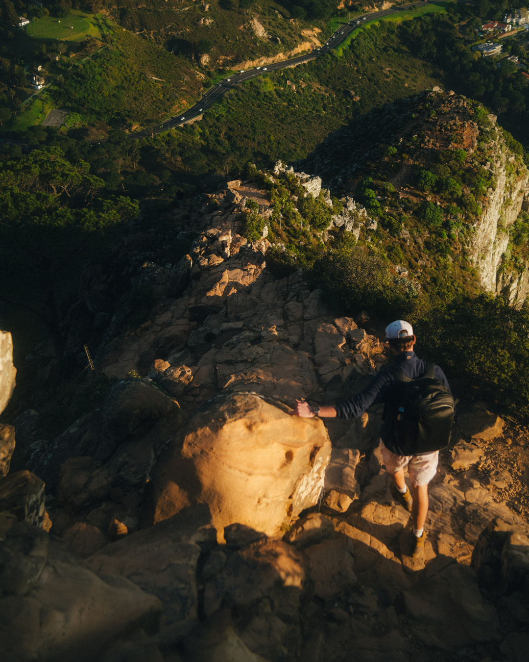 Man wearing black hybrid backpack climbs down Lions Head mountain in Cape Town