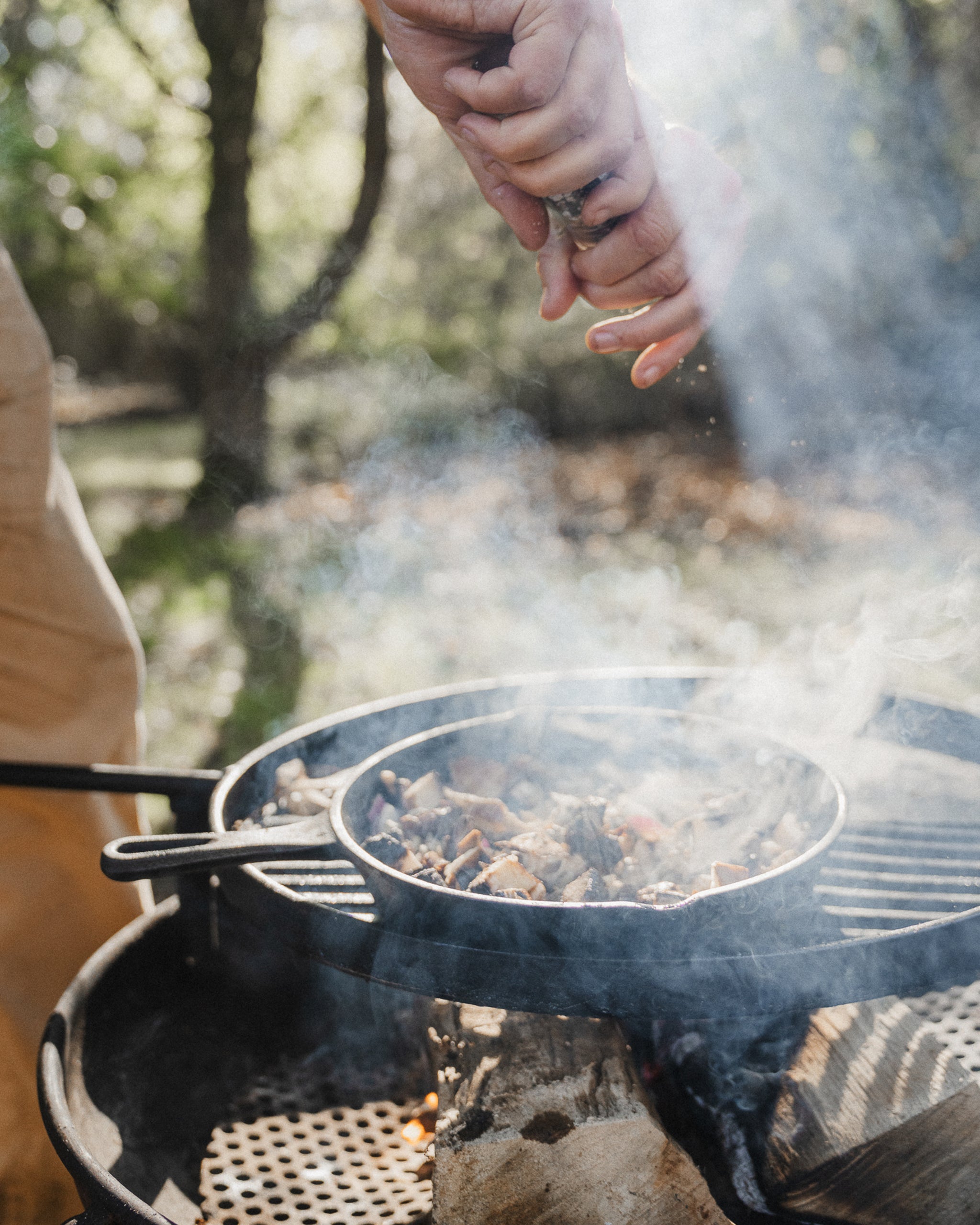 a man cooking a bbq in the forest - the travel project blog