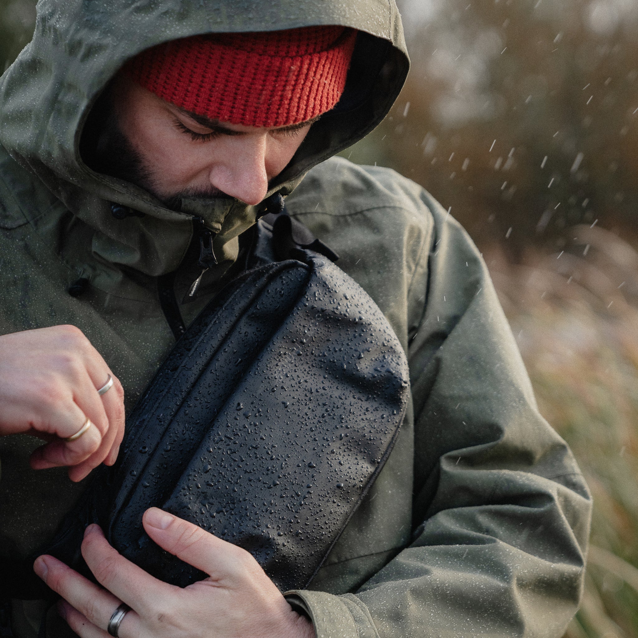 a man in the rain wearing a black crossbody on his chest - the travel project blog