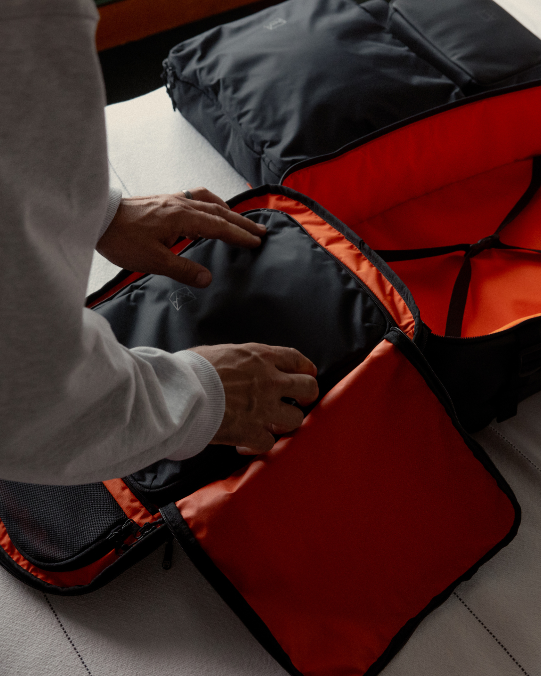 Man unpacking packing cubes from a hybrid backpack, with the orange interior visible.