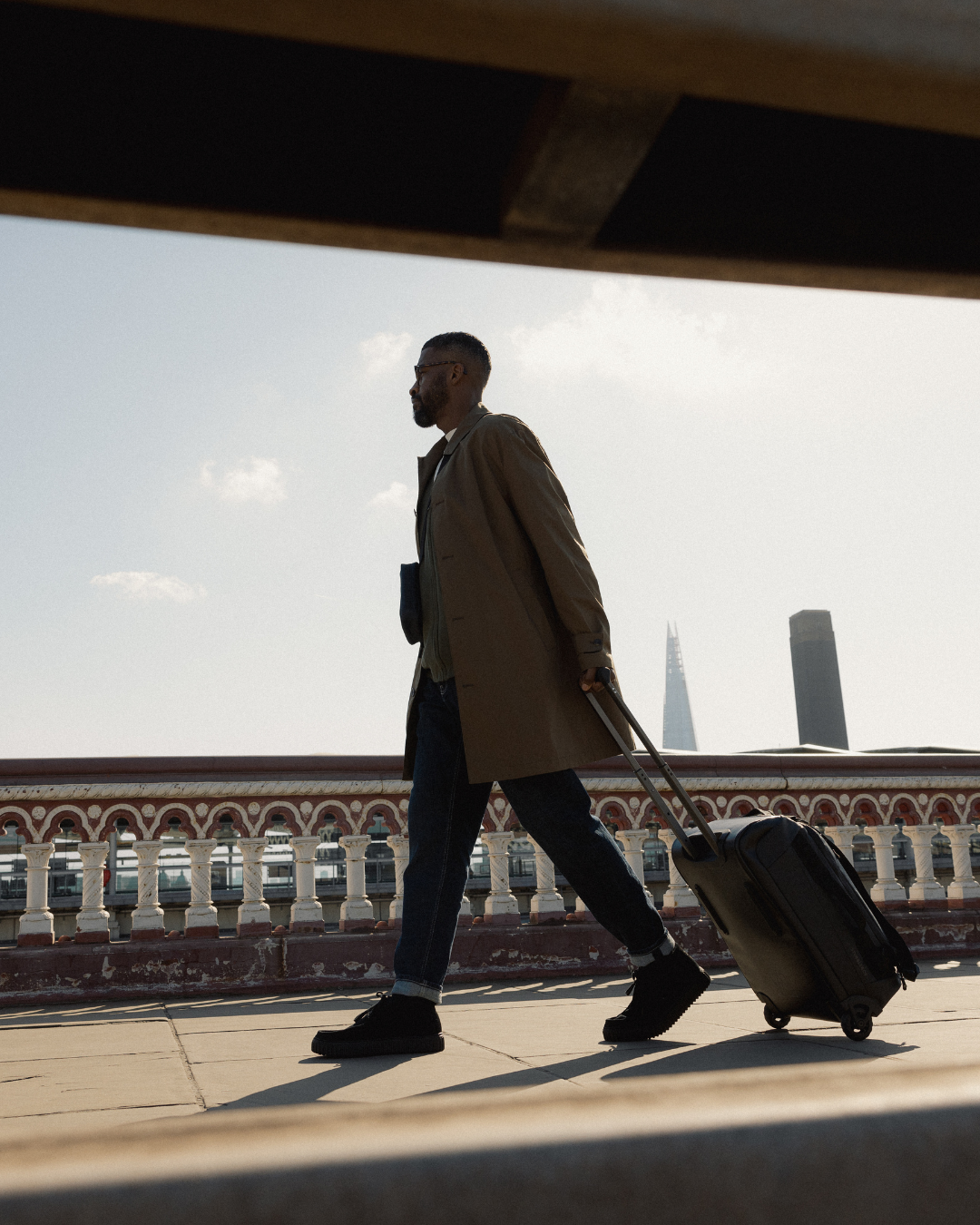 Man pulling along the All Black Wheeled Duffel 40L, with the Shard visible in the background.