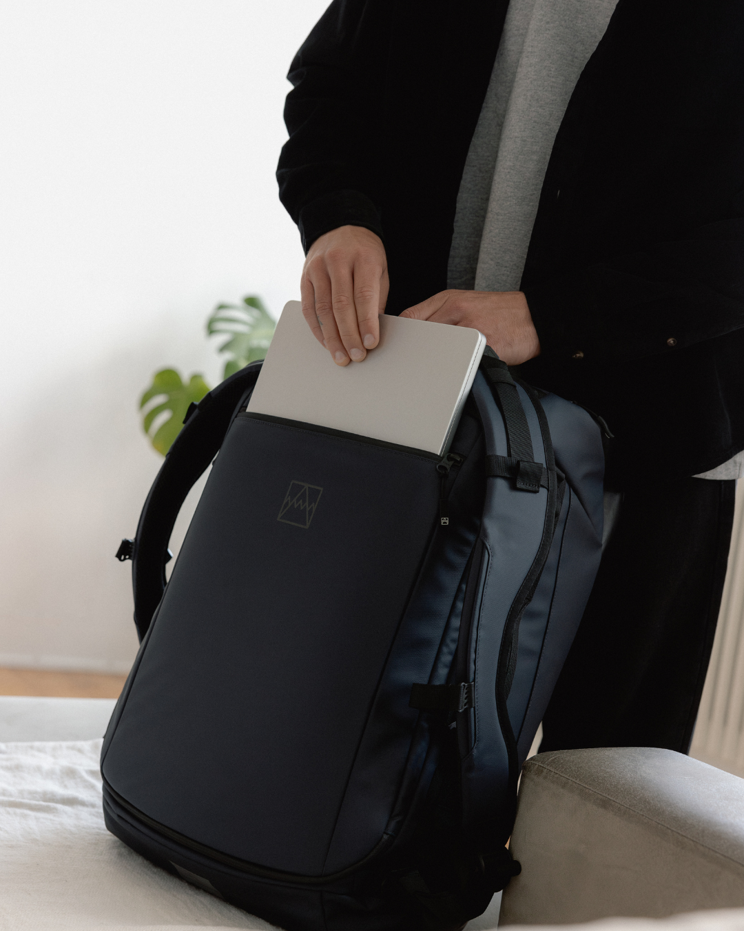 Man removing a laptop from the laptop compartment of the Midnight Blue Kit Bag.