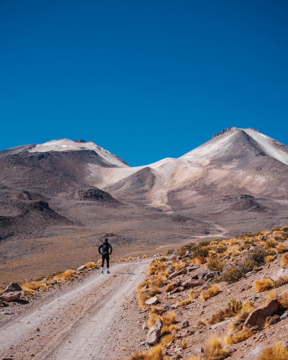 Person standing on a road in a desert landscape with mountains in the background