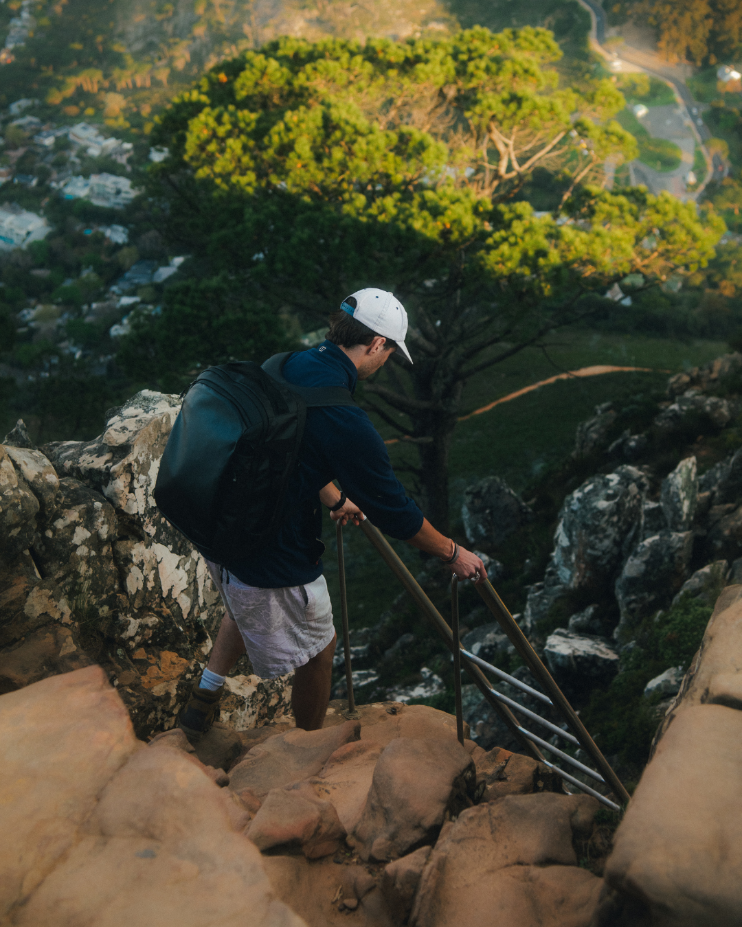 Man wearing black Hybrid backpack climbing down Lion's Head Mountain in Cape Town