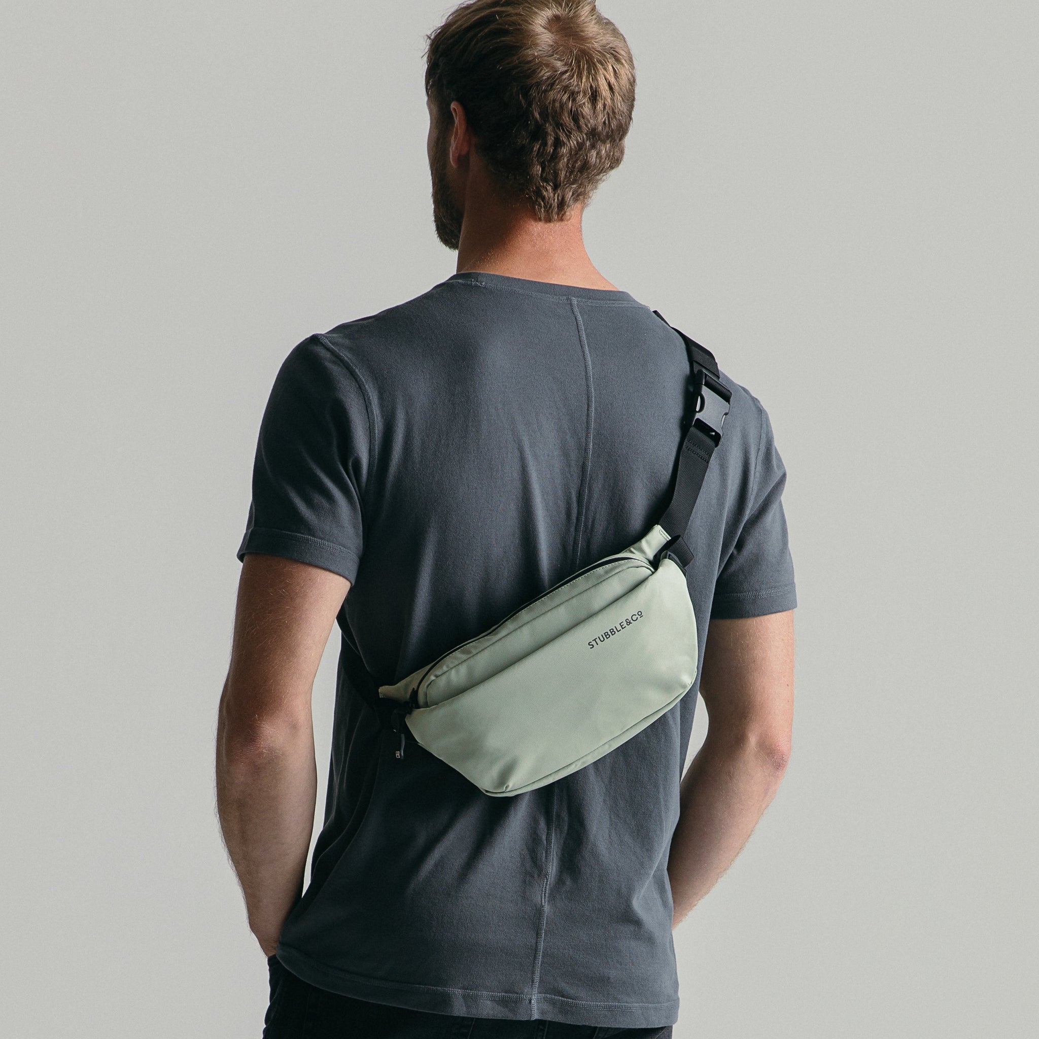 Back view of man wearing crossbody bag in Matcha green