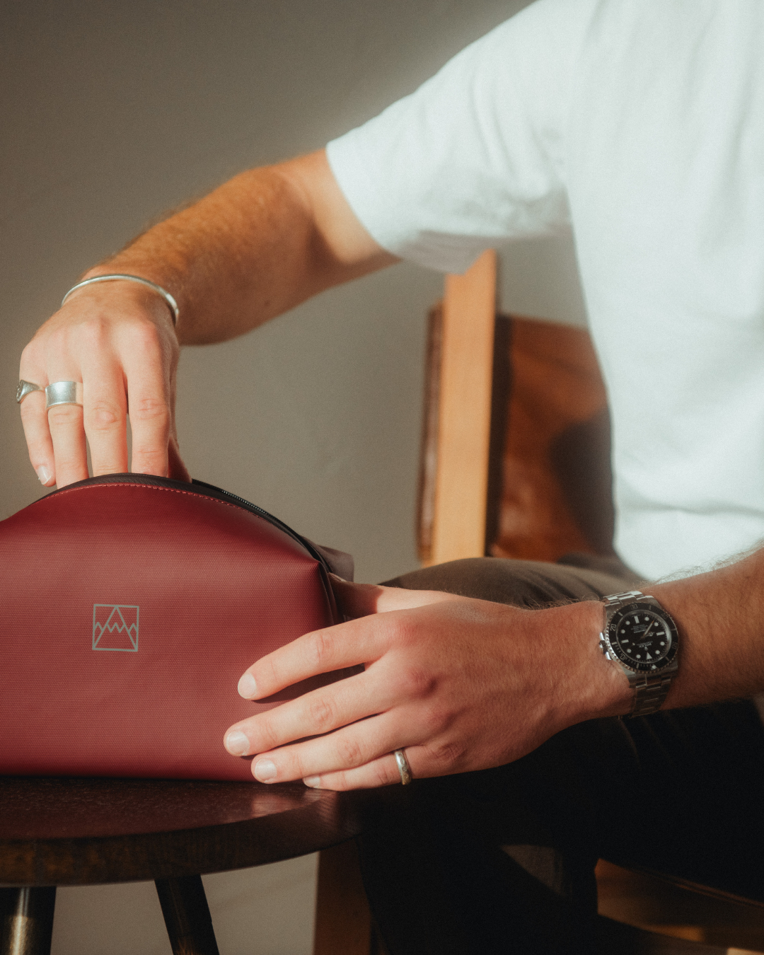 Man in a white T-shirt pulling toiletries out of the Garnet Red Wash Bag.