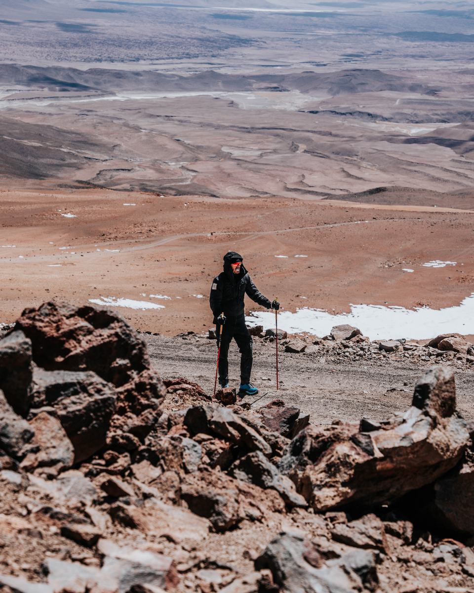 Person walking on a rocky mountain with a rugid landscape in the background