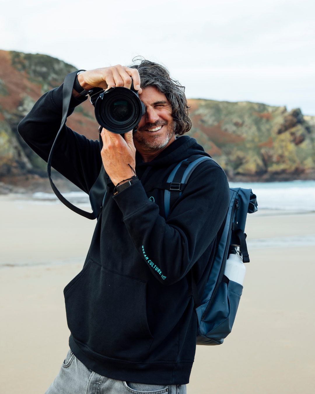 Matt Porteous taking a photo with his camera at a beach in Jersey