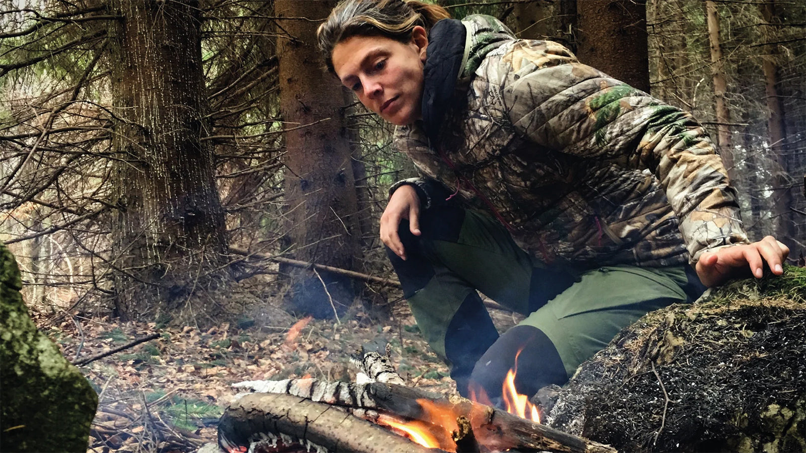 Megan Hine in the forest with a campfire