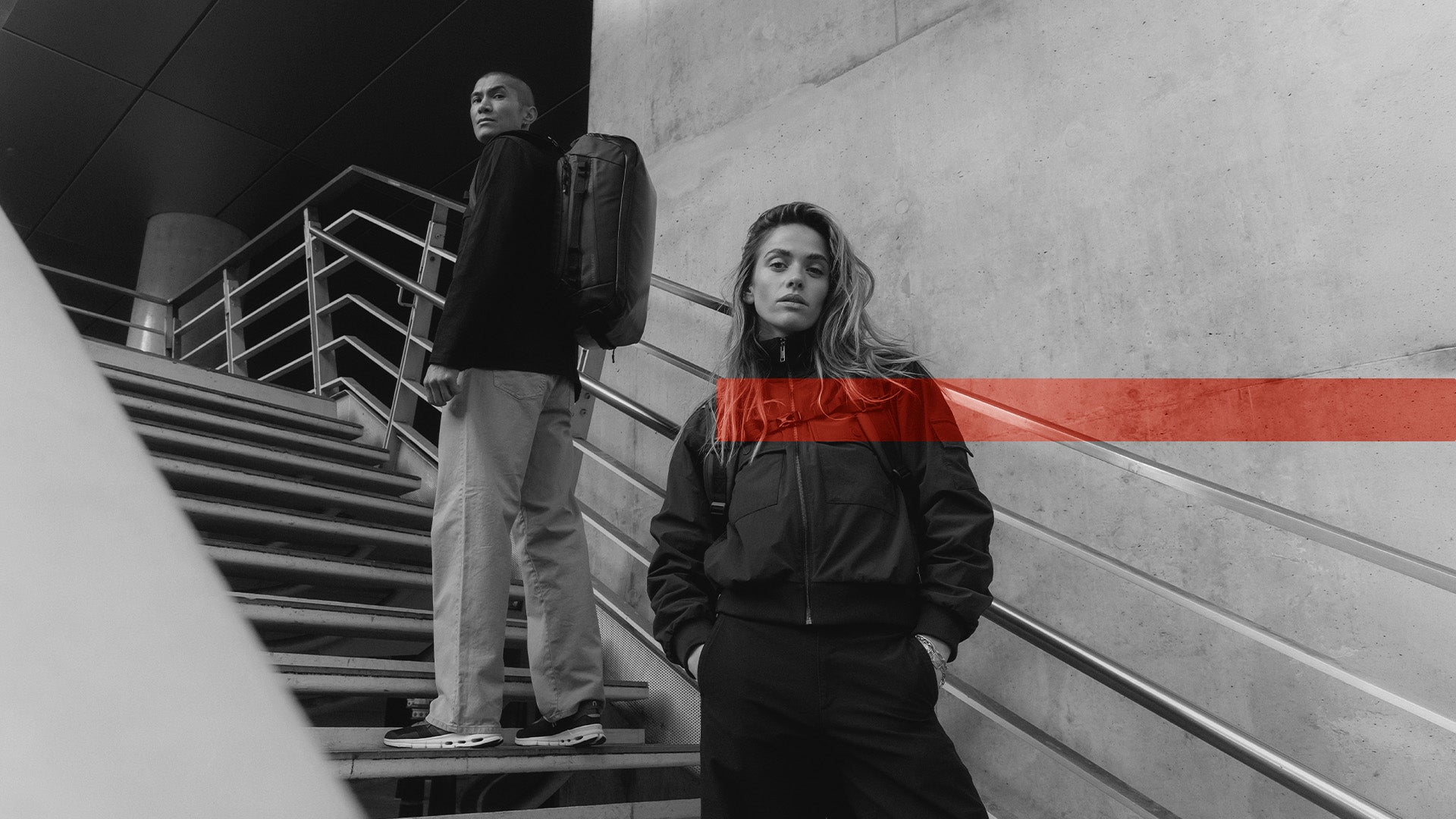A man and woman standing on differetn stairs on a staircase with kit bag 40l on their backs with the members week creative overlayed