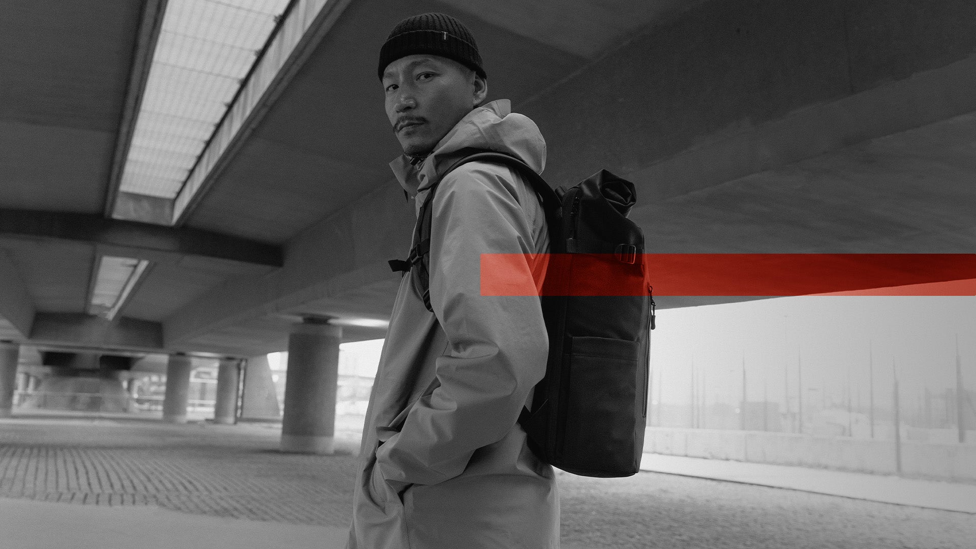 A man looking into the camera with a Black Roll Top 20L on his back and the Members Week creative as an overlay