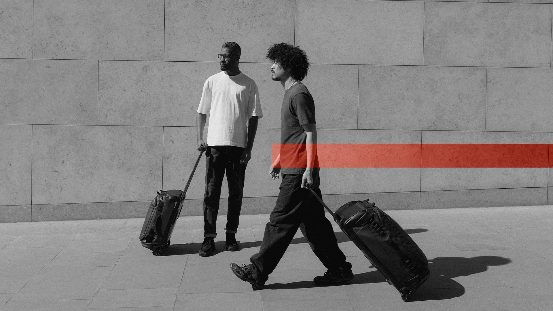 Two men walking with their wheeled duffel  bags in 40l and 80l in Black and White with the Members Week Creative overlayed
