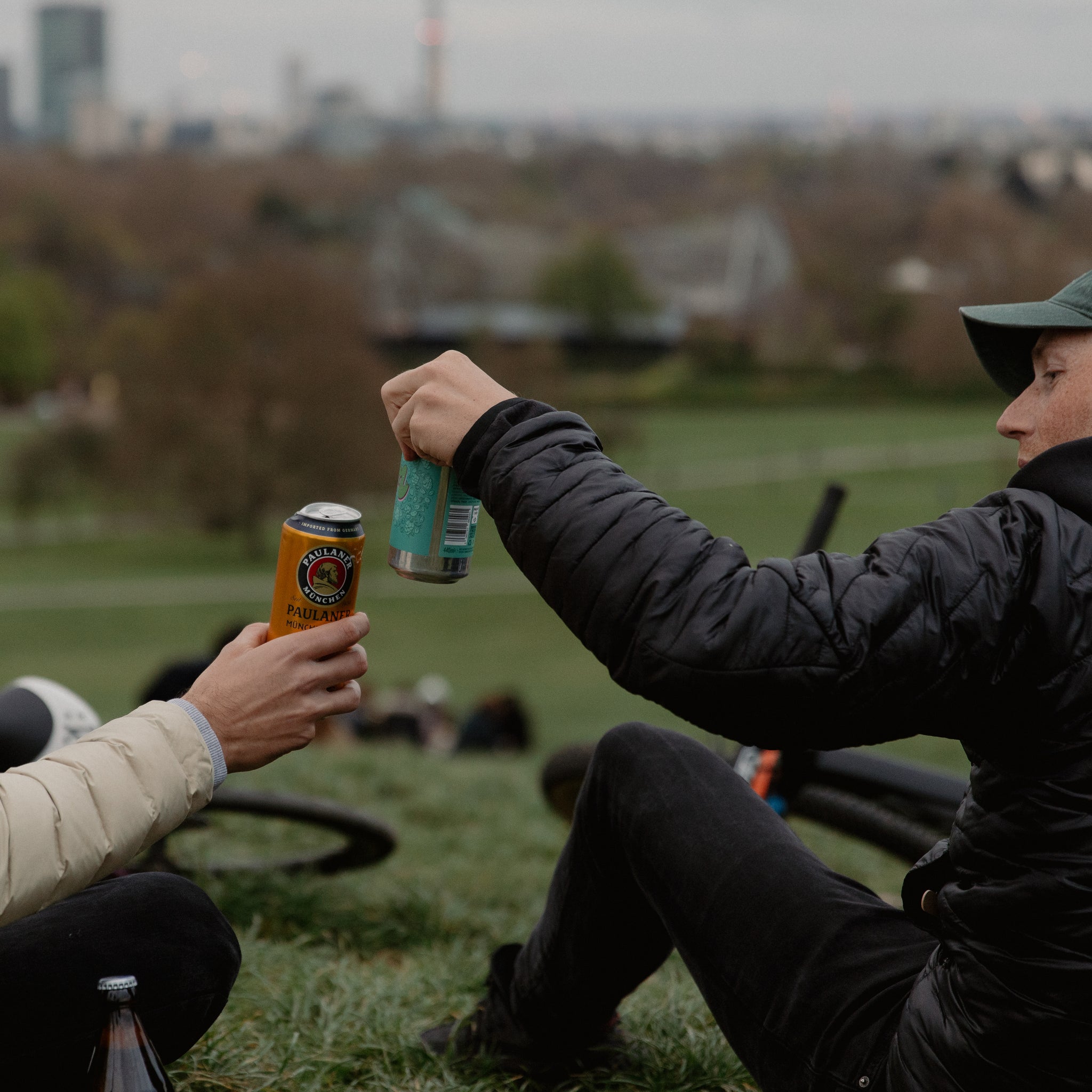 2 people cheersing their drinks in a park