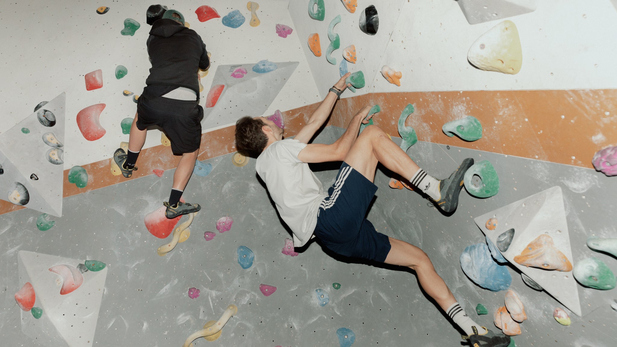 2 men climbing up an inside climbing wall