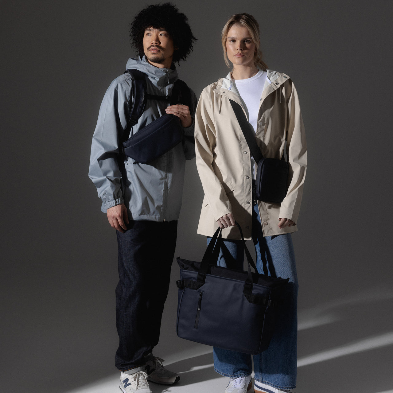 A studio shot of two models wearing the Midnight Blue collection of bags