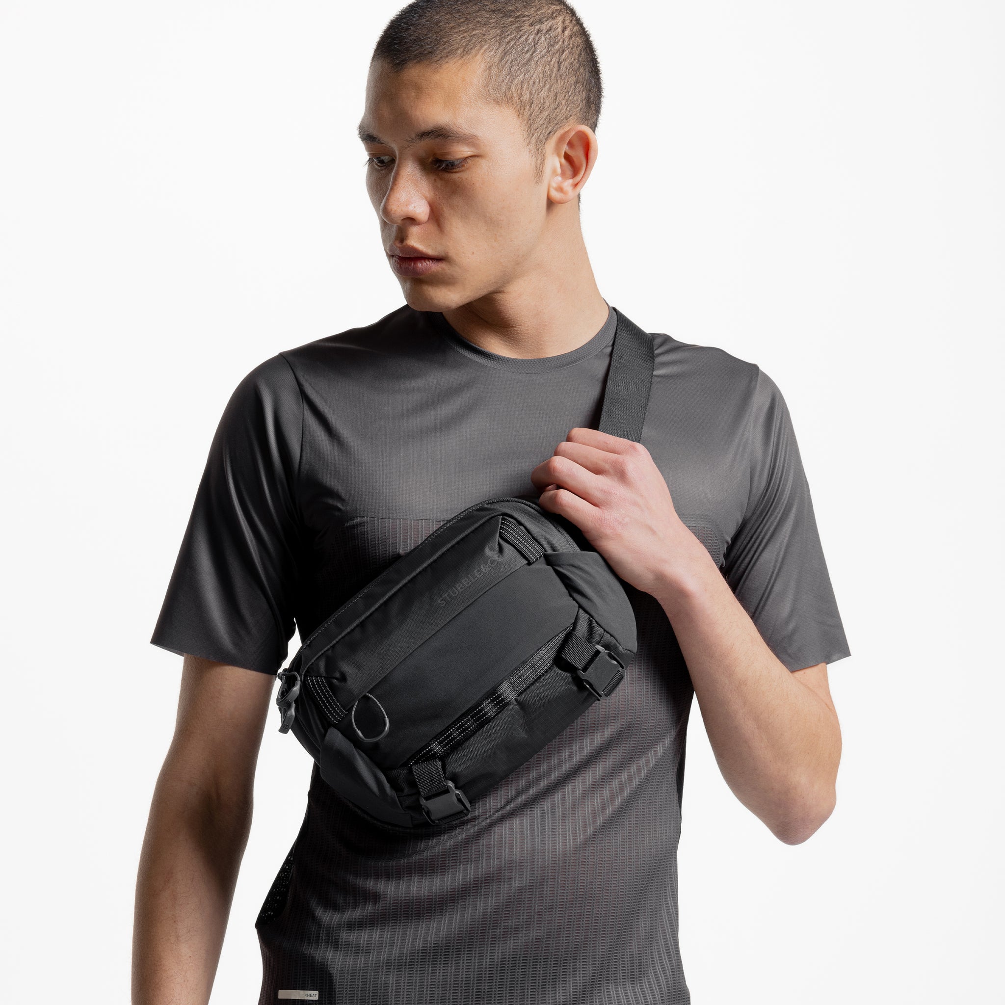 A man wearing the Charcoal Motion Sling 4L across his chest as a crossbody