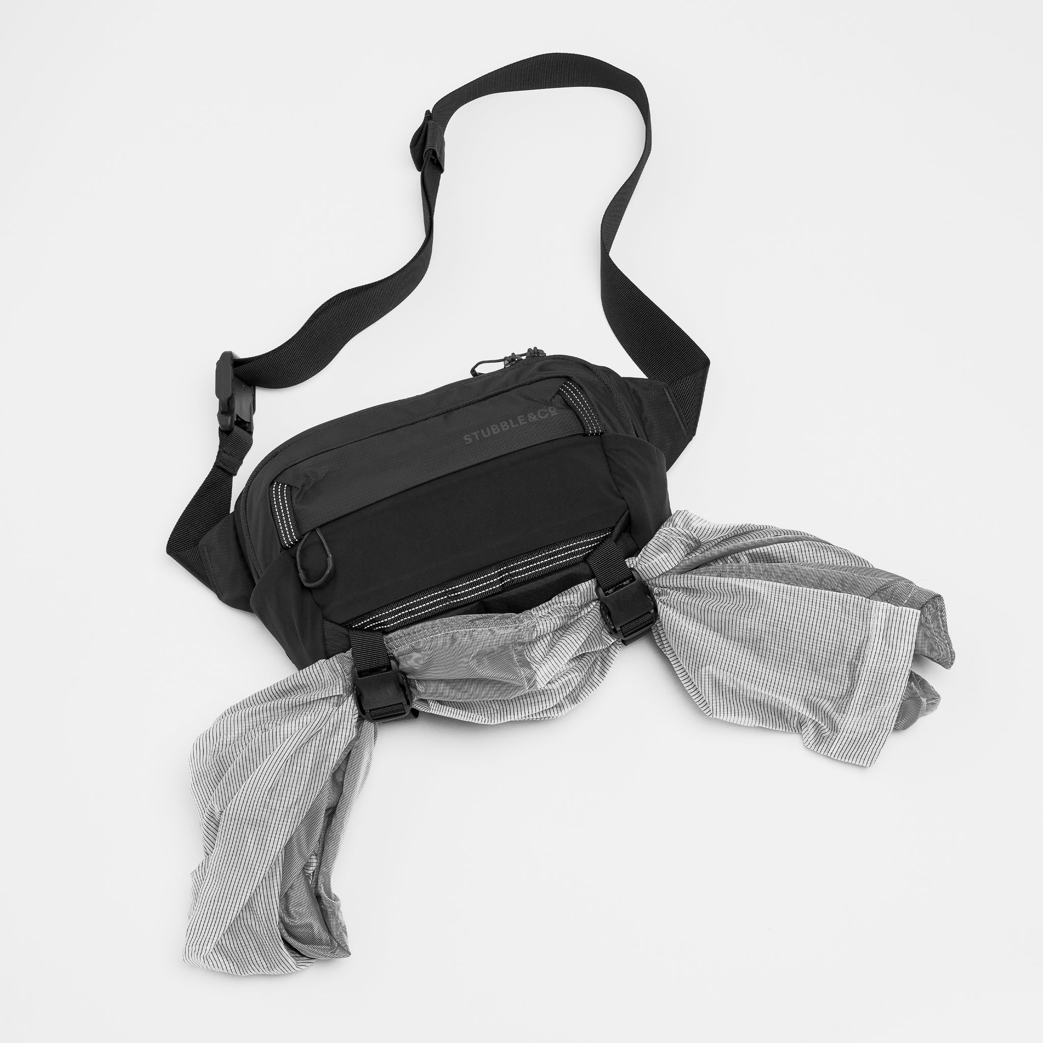 A stdio shot of the extra gear clips and quick release clips on the Charcoal Motion Sling 4L as well as Magma and Ash