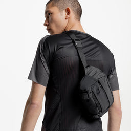 A studio shot of a man wearing the Charcoal Motion Sling 4L across his back