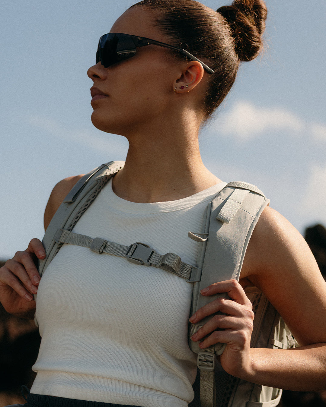 A woman wearing a motion adventure pack 38l in Ash holding the chest strap