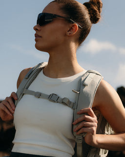 A woman wearing a motion adventure pack 38l in Ash holding the chest strap