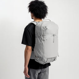 A studio shot of a model wearing the Motion Adventure Backpack 38L in Ash on his back