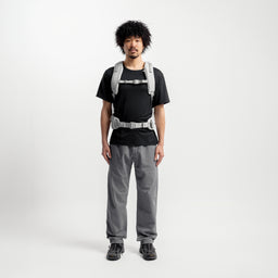A studio shot of a model wearing the Motion Adventure Pack 38L in Ash with the chest and waist strap done up 
