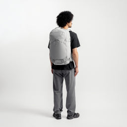 A model standing in a studio with a Motion Adventure Pack 38L on his back in Ash 