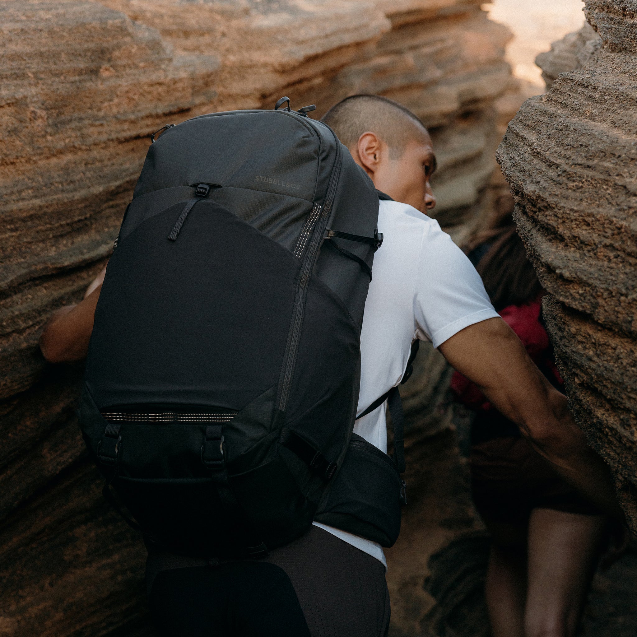 A man walking through a cave wearing a Motion Adventure Pack 38L in Charcoal on his back