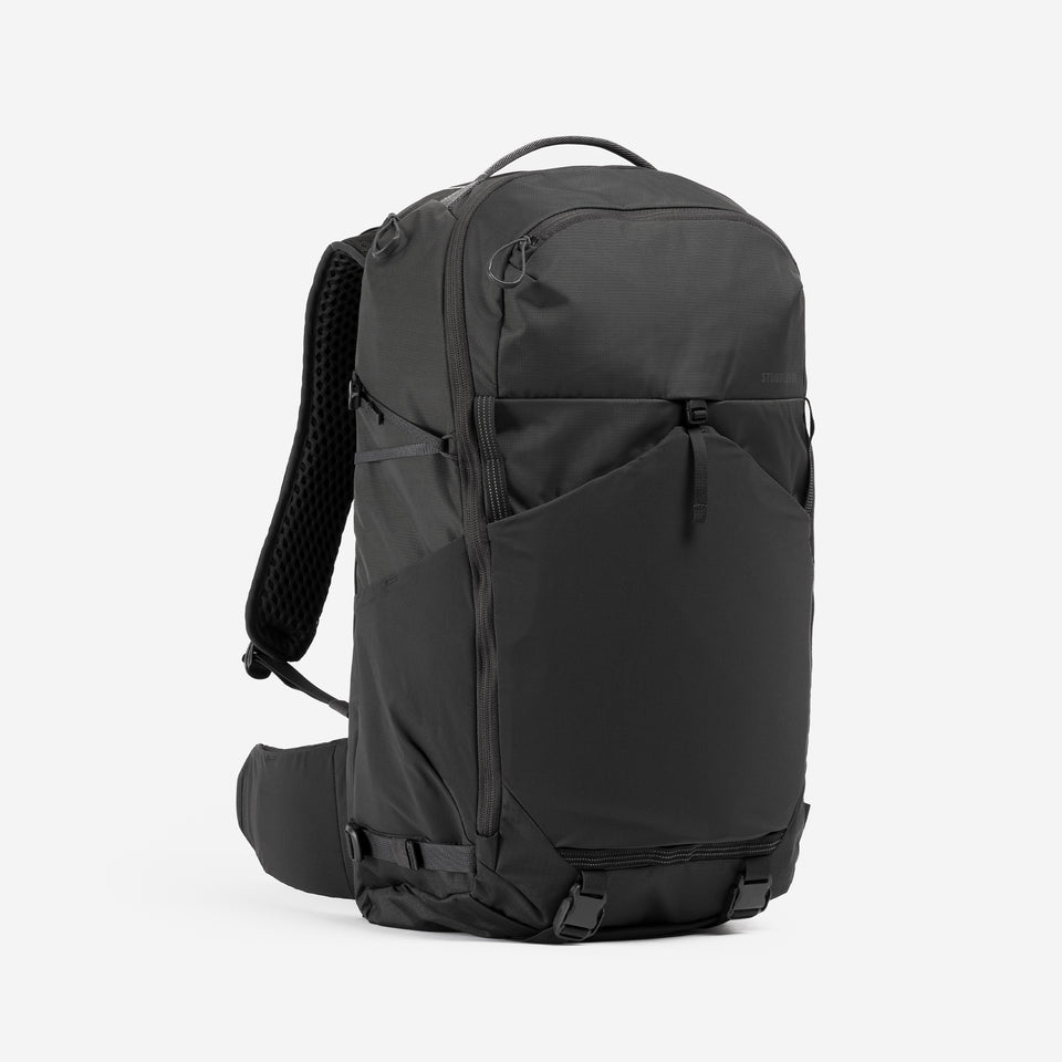 A studio shot of the front and side of the Motion Adventure Pack 38L in Charcoal